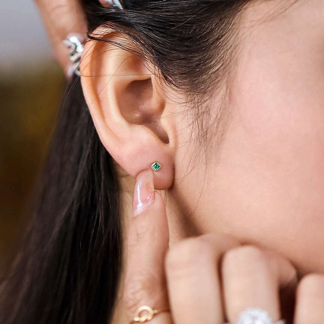 Oreja con topito en forma de cuadrado en oro amarillo de 18 quilates con esmeralda, hechos en Joyería Caracas. 