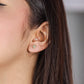 Oreja de mujer con topito en forma de cruz en oro amarillo de 18 quilates con 6 cristales de color blanco, hecho en Joyería Caracas. 