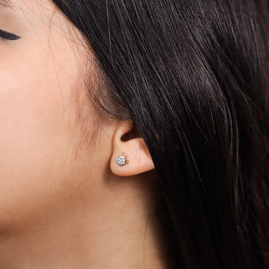 Oreja de mujer con topito en forma de tetera en oro de 18 quilates con cristales de color blanco hecho en joyeria caracas. 