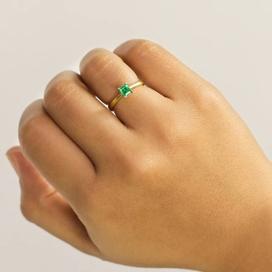 Mano de mujer con anillo en oro amarillo de 18 quilates con esmeralda en corte cuadrado, hecho en Joyería Caracas. 