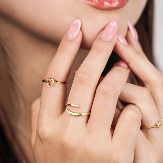 Mano de mujer con anillo con forma de corazón en el centro en oro amarillo de 18 quilates, hecho en Joyería Caracas. 