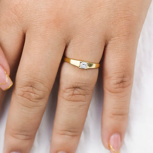 Mano de mujer con anillo en oro amarillo de 18 quilates con Diamante en el centro de color blanco, cuenta con certificado de calidad y garantía de por vida, hecho en Joyería Caracas. 