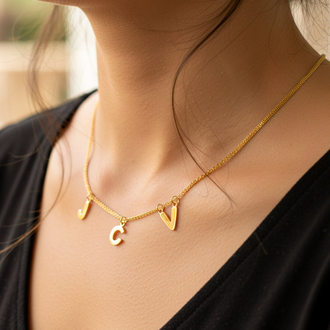 Cuello de mujer usando una gargantilla con 3 iniciales de letras J,C y V en oro amarillo de 18 quilates de Joyería Caracas. 