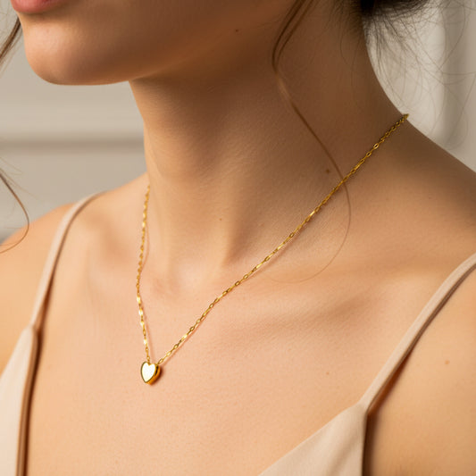 Cuello de mujer usando una gargantilla con dije en forma de corazón pasante L en oro amarillo de 18 quilates de Joyería Caracas. 