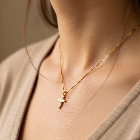 Cuello de mujer usando una gargantilla con cadena en tejido Venecia con dije en forma de cruz en oro amarillo de 18 quilates de Joyería Caracas. 