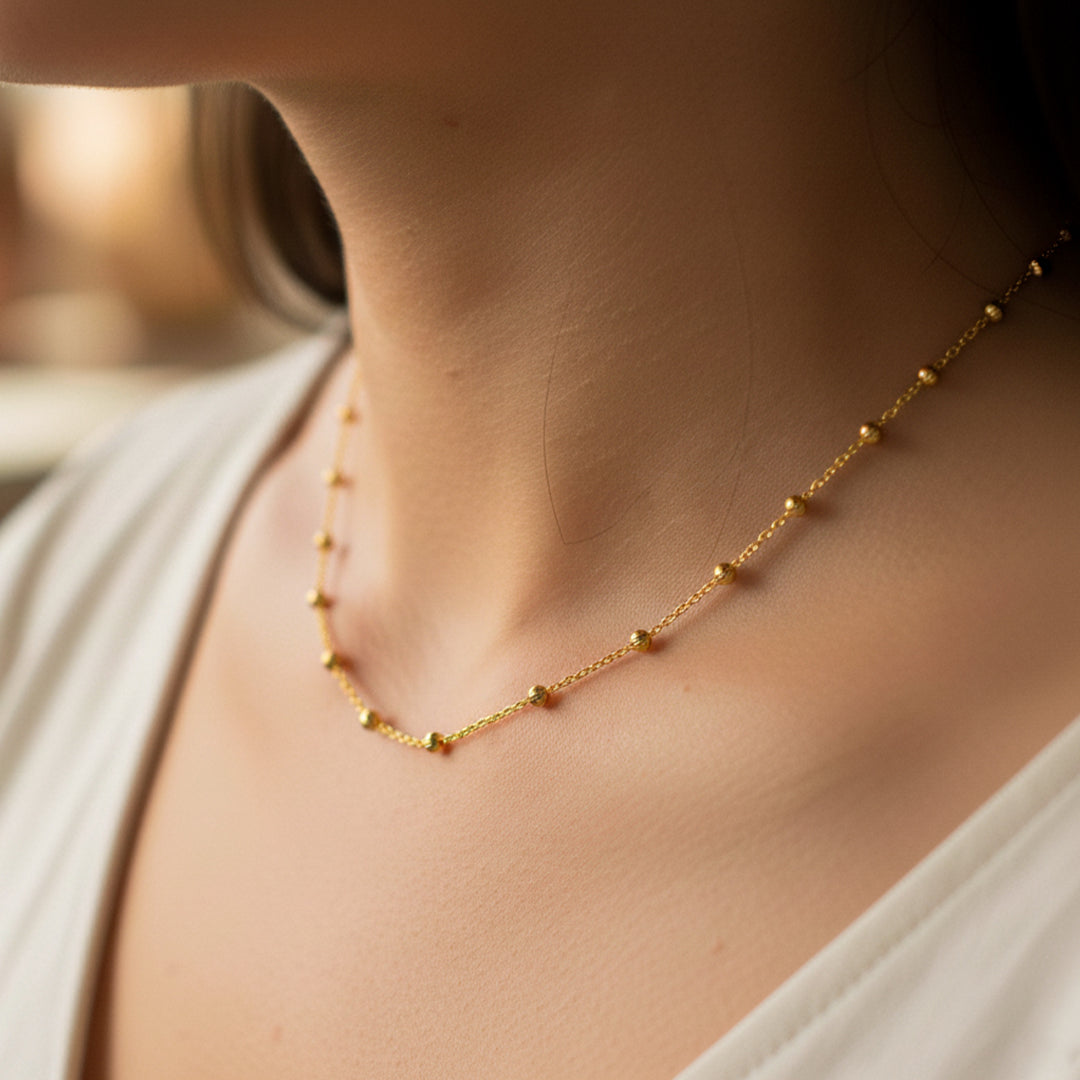 Cuello de mujer usando una gargantilla de esferas facetadas en oro amarillo de 18 quilates de Joyería Caracas. 