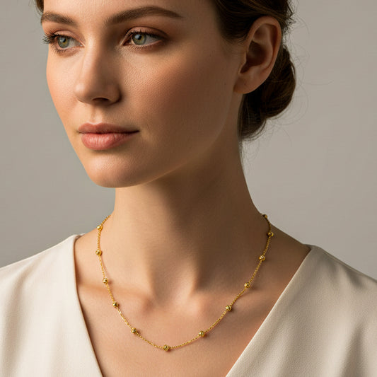 Cuello de mujer usando una gargantilla de esferas facetadas en oro amarillo de 18 quilates de Joyería Caracas. 