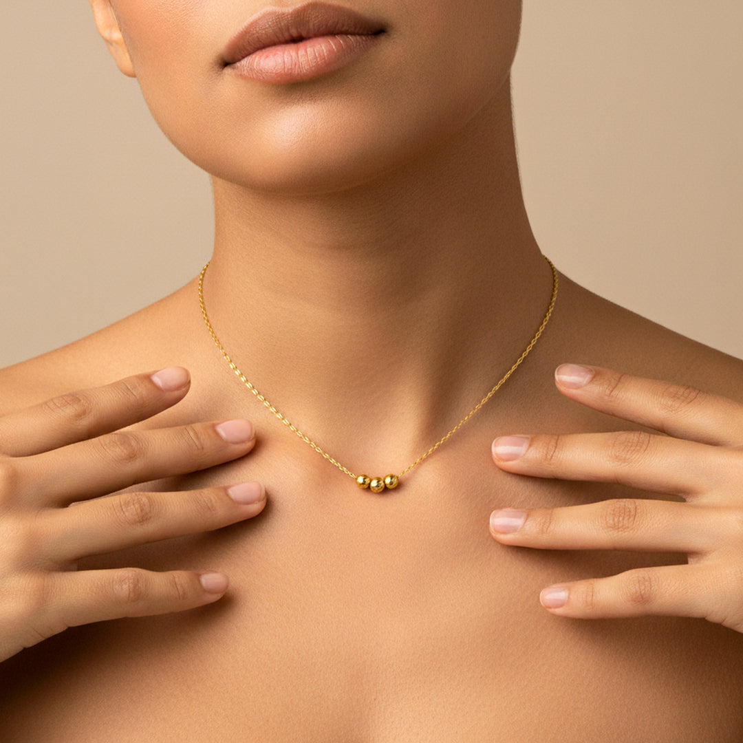Cuello de mujer usando una gargantilla con 3 esferas en oro amarillo de 18 quilates de Joyería Caracas. 
