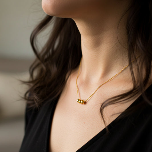 Cuello de mujer usando una gargantilla con 3 esferas lisas en oro amarillo de 18 quilates de Joyería Caracas. 
