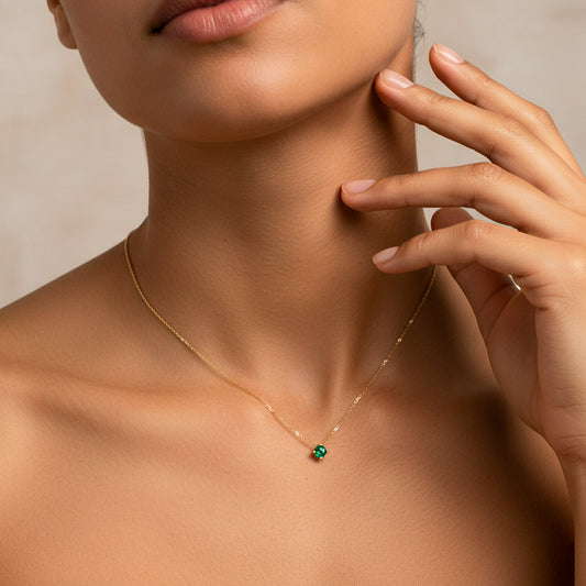 Cuello de mujer usando una gargantilla con dije pasante de esmeralda redonda de color verde de Joyería Caracas. 