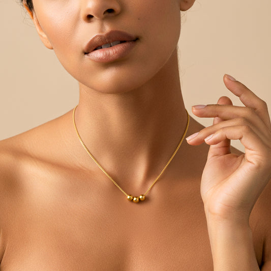 Cuello de mujer usando una gargantilla con cadena mini cubana con 3 esferas lisas de 50cm en oro amarillo de 18 quilates de Joyería Caracas. 