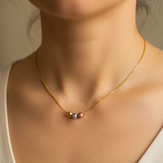 Cuello de mujer usando una gargantilla con cadena en tejido mini cubana con 3 esferas de 3 oros de 18 quilates de Joyería Caracas. 