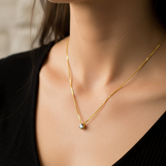 Cuello de mujer usando una gargantilla mini cubana en oro amarillo de 18 quilates con dije pasante con cristal de color blanco de Joyería Caracas. 