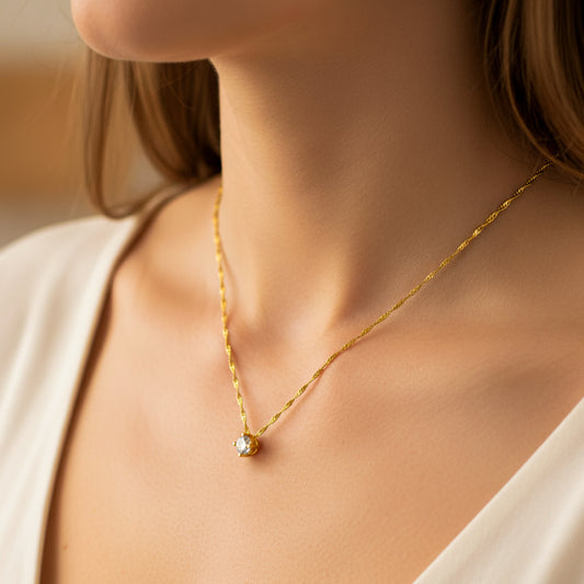 Cuello de mujer usando una gargantilla con cadena en tejido Singapur en oro amarillo de 18 quilates con dije pasante con cristal de color blanco de Joyería Caracas. 