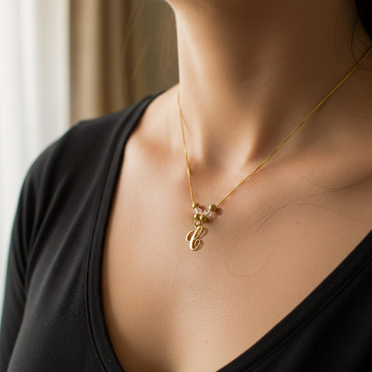 Cuello de mujer usando una gargantilla con cadena en tejido Venecia con dije de letras clásicas en oro amarillo de 18 quilates de Joyería Caracas. 