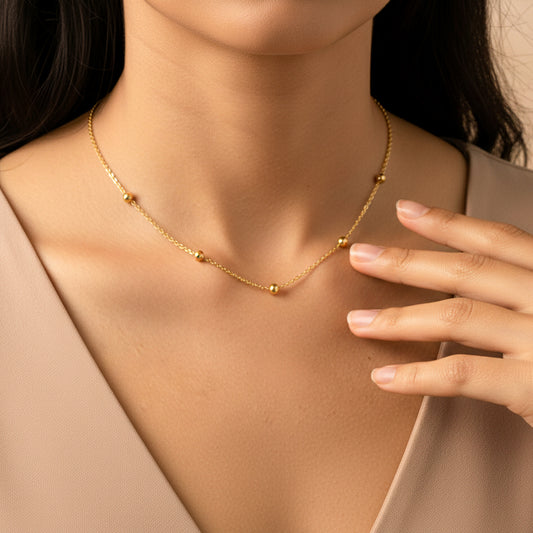 Cuello de mujer usando una gargantilla de esferas lisas en oro amarillo de 18 quilates de Joyería Caracas. 