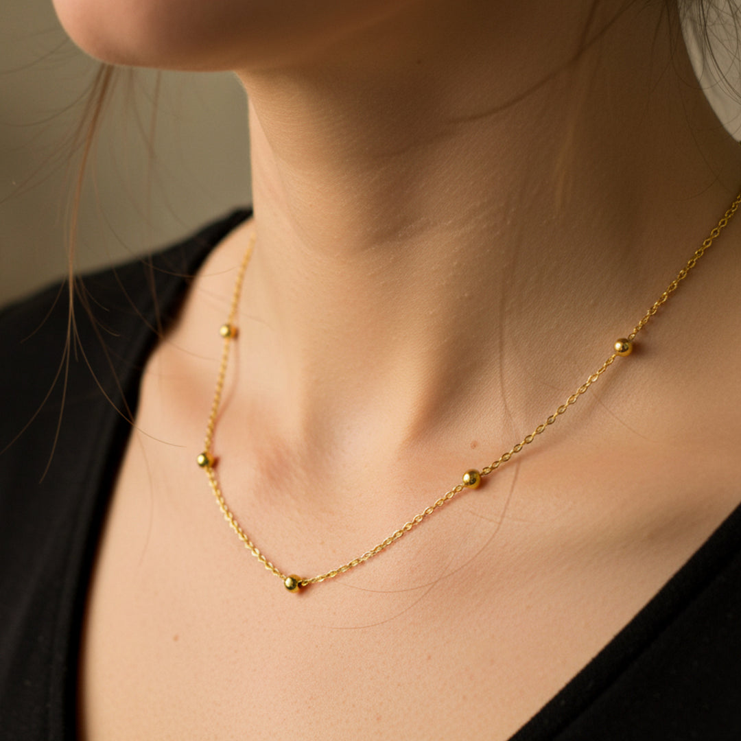 Cuello de mujer usando una gargantilla de esferas en oro amarillo de 18 quilates de Joyería Caracas. 