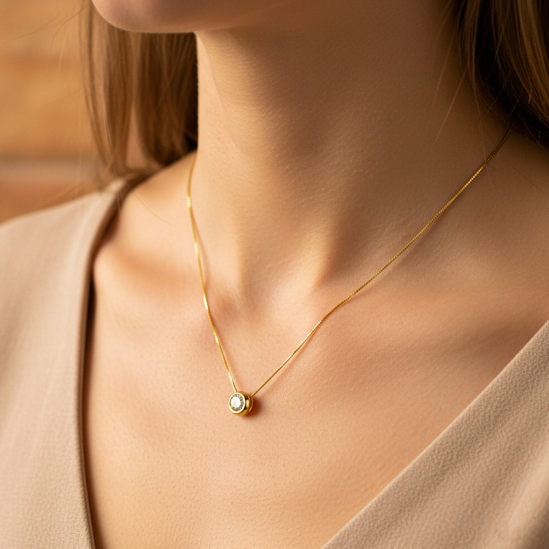 Cuello de mujer usando una gargantilla en tejido Venecia con dije de dona pasante en oro amarillo de 18 quilates y cristal redondo de color blanco de Joyería Caracas. 