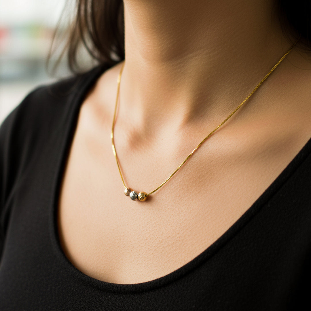 Cuello de mujer usando una gargantilla con cadena en tejido Venecia con 3 esferas en oro amarillo, blanco y rosa de 18 quilates de Joyería Caracas. 