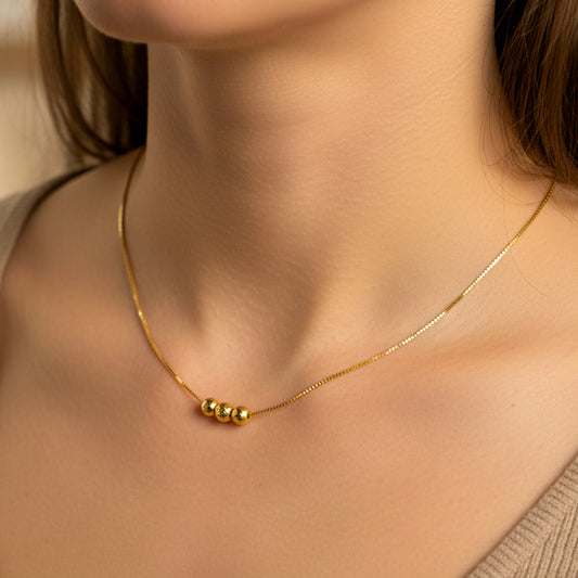 Cuello de mujer usando una gargantilla con cadena en tejido Venecia con 3 esferas facetadas en oro amarillo de 18 quilates de Joyería Caracas. 