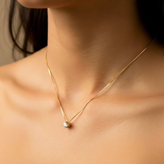 Cuello de mujer usando una gargantilla veneciana con dije pasante en oro amarillo de 18 quilates con cristal redondo de color blanco de Joyería Caracas. 