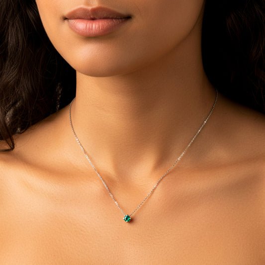 Cuello de mujer usando una gargantilla en oro blanco de 18 quilates con un dije pasante de Esmeralda de color verde de  Joyería Caracas. 