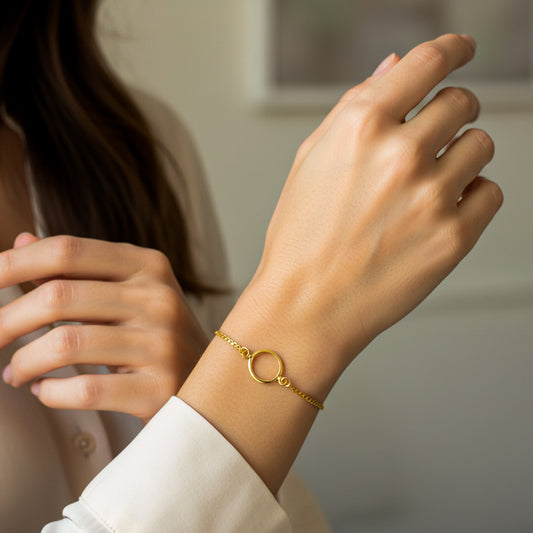 Mano de mujer usando una pulsera en tejido bismarck con un herraje en el centro de aro sin fin en oro amarillo de 18 quilates. 