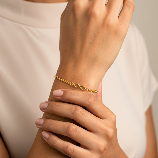 Mano de mujer usando una pulsera bismarck con herraje de infinito en oro amarillo de 18 quilates de Joyería Caracas. 