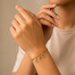 Mano de mujer usando una pulsera en tejido bismarck con dijes de iniciales de la letra A, F Y G en oro amarillo de 18 quilates con cristales de color blanco de Joyería Caracas. 