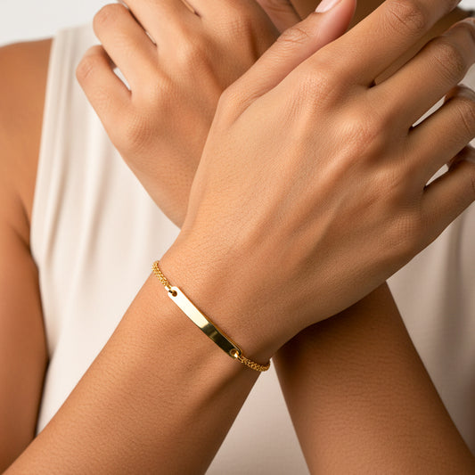 Mano de mujer usando una pulsera en tejido Bismarck con esclava lisa en oro amarillo de 18 quilates de Joyería Caracas. 