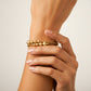 Mano de mujer usando una pulsera brazalete diamantada con esfera con textura tipo arena en oro amarillo de 18 quilates de Joyería Caracas. 