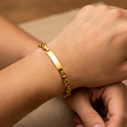 Mano de mujer usando una pulsera en tejido Calabrote con esclava en oro amarillo de 18 quilates de Joyería Caracas. 
