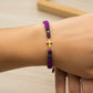 Mano de modelo usando una pulsera tejida con la forma de una cruz en oro amarillo de 18 quilates con bisutería de calidad de Joyería Caracas. 