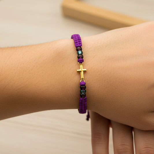 Mano de modelo usando una pulsera tejida con la forma de una cruz en oro amarillo de 18 quilates con bisutería de calidad de Joyería Caracas. 