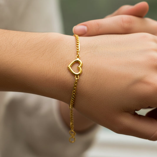 Mano de mujer usando una pulsera en tejido cubano con corazón en el centro en oro amarillo de 18 quilates de Joyería Caracas. 