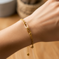 Mano de mujer usando una pulsera cubana con clips y círculos en oro amarillo de 18 quilates de Joyería Caracas. 
