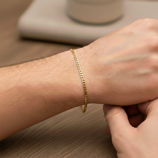 Mano de hombre usando una pulsera cubana seguida en oro amarillo de 18 quilates de Joyería Caracas. 