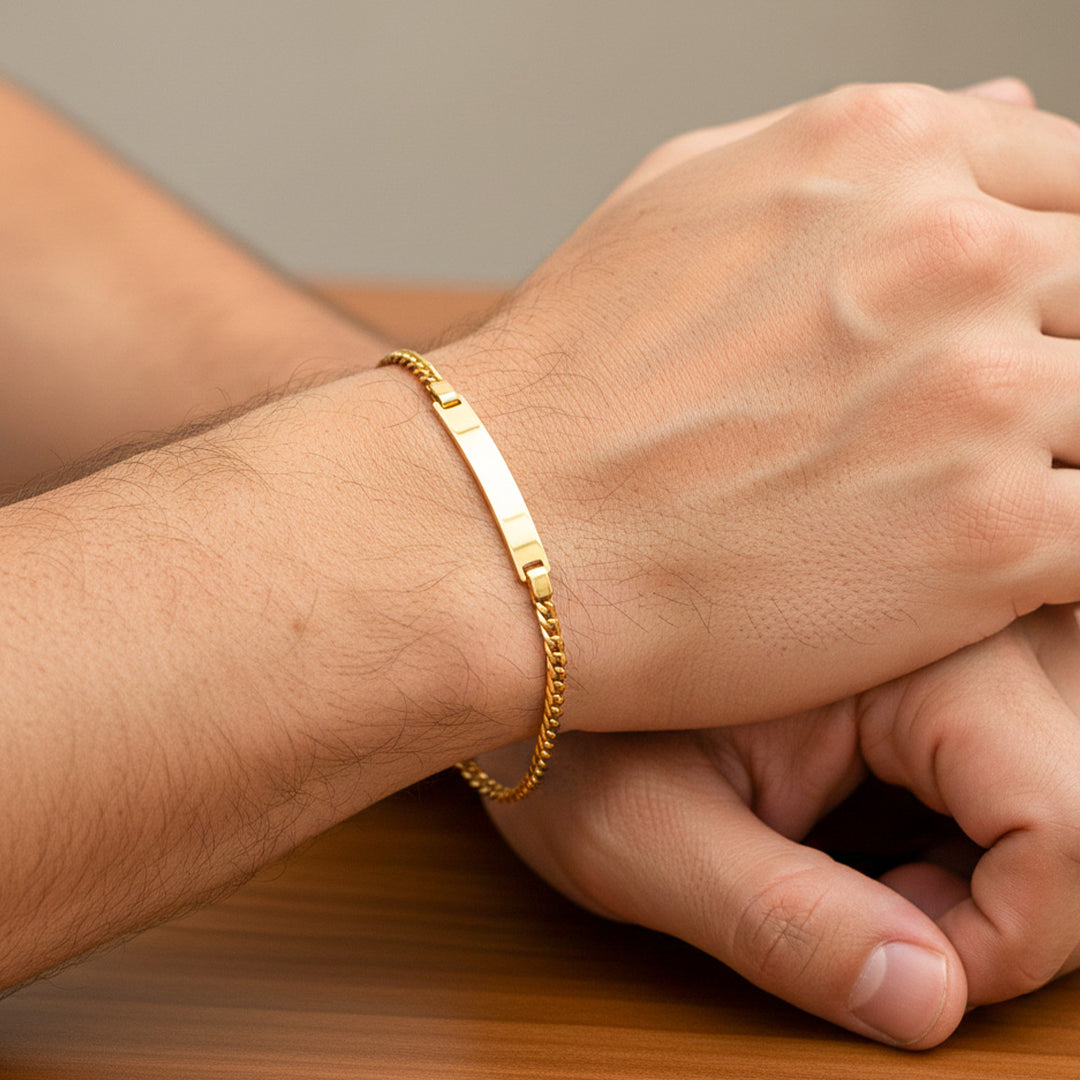 Mano de hombre usando una pulsera cubana seguida con esclava en oro amarillo de 18 quilates de Joyería Caracas. 