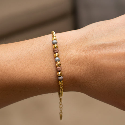 Mano de mujer usando una pulsera con esferas diamantadas de 3 oros de 18 quilates de Joyería Caracas. 