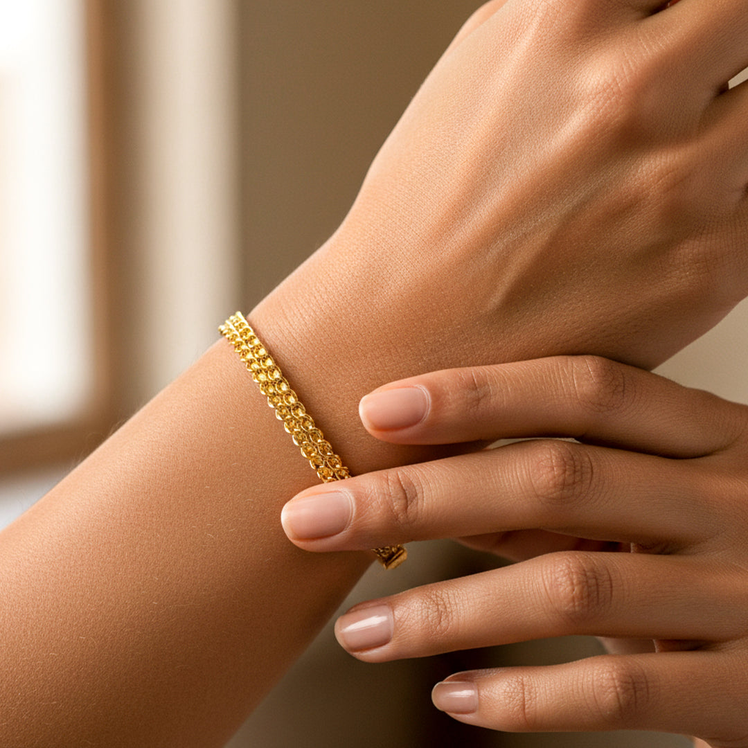 Mano de mujer usando una pulsera doble faz en oro amarillo de 18 quilates de Joyería Caracas. 
