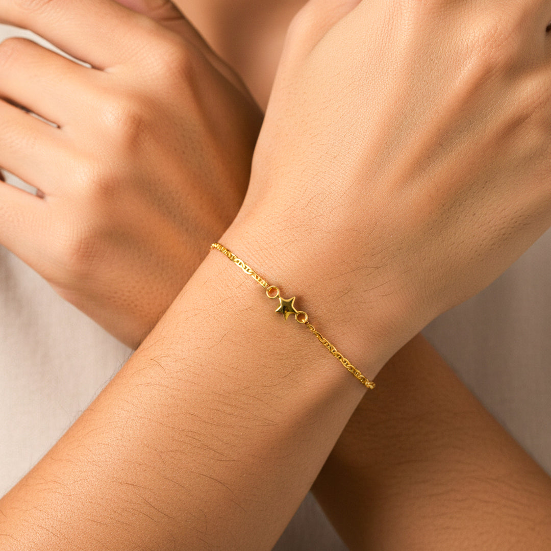 Mano de mujer usando una pulsera en tejido escalera plana con herraje de estrella en oro amarillo de 18 quilates de Joyería Caracas. 