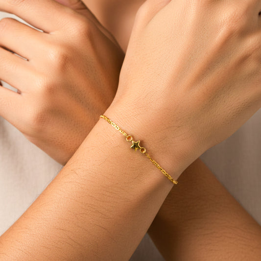 Mano de mujer usando una pulsera en tejido escalera plana con herraje de estrella en oro amarillo de 18 quilates de Joyería Caracas. 