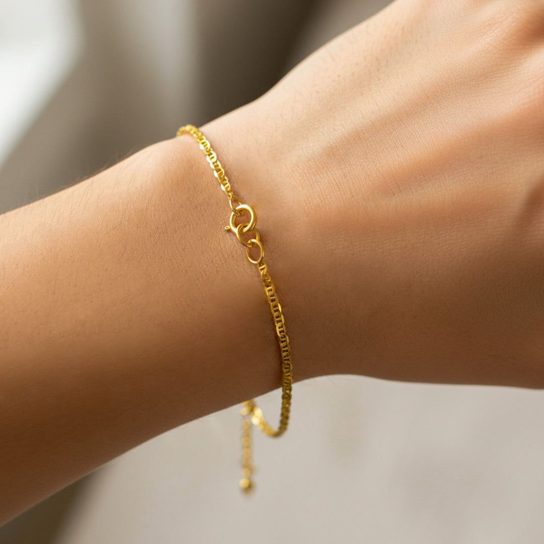 Mano de mujer usando una pulsera en tejido escalera plana lisa en oro amarillo de 18 quilates de Joyería Caracas. 