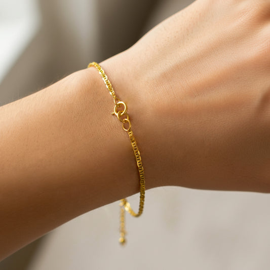 Mano de mujer usando una pulsera en tejido escalera plana lisa en oro amarillo de 18 quilates de Joyería Caracas. 
