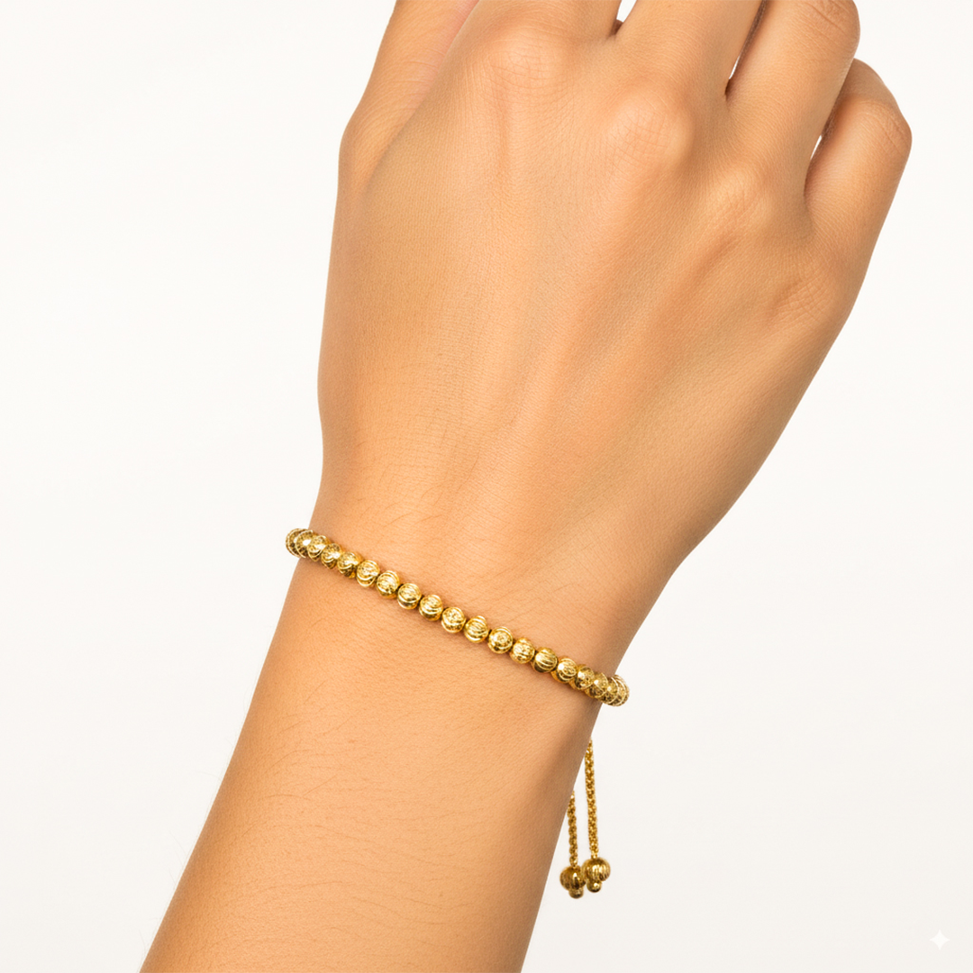 Mano de mujer usando una pulsera con esferas facetadas en oro amarillo de 18 quilates de Joyería Caracas. 