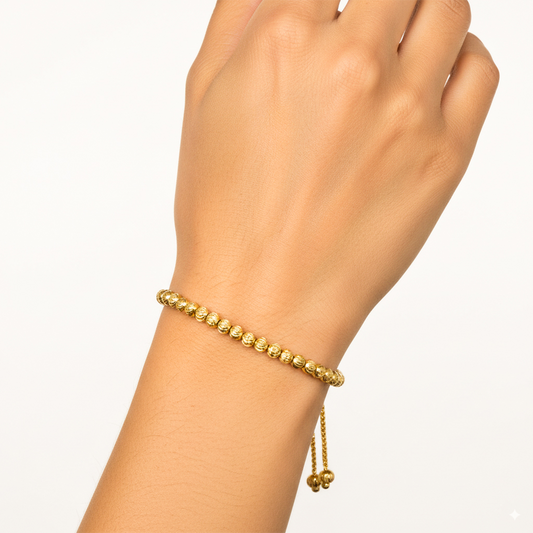 Mano de mujer usando una pulsera con esferas facetadas en oro amarillo de 18 quilates de Joyería Caracas. 