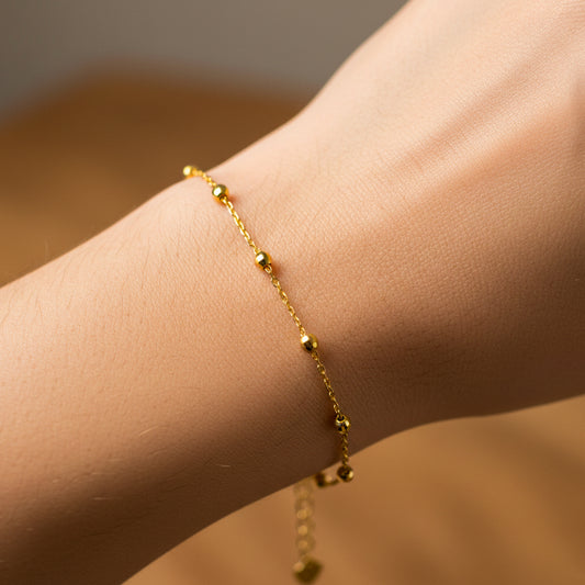 Mano de mujer usando una pulsera con esferas facetadas en oro amarillo de 18 quilates de Joyería Caracas. 
