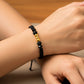Mano de modelo usando una pulsera tejida con hilo color negro, con esferas lisas y facetada en oro amarillo de 18 quilates con bisutería de calidad de Joyería Caracas. 