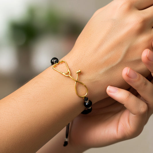 Mano de modelo usando una pulsera tejida en hilo color negro, con herraje de estetoscopio en oro amarillo de 18 quilates de Joyería Caracas. 