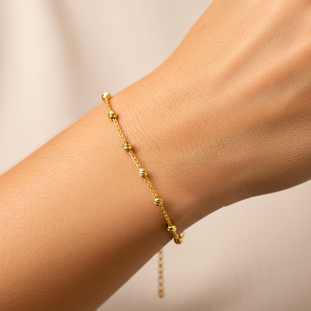 Mano de mujer usando una pulsera con esferas facetadas en oro amarillo de 18 quilates de Joyería Caracas. 